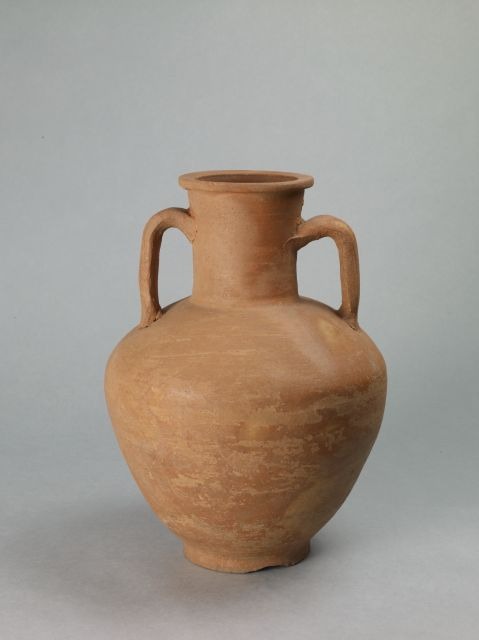 Red-brown ceramic amphora with two handles against a grey background.